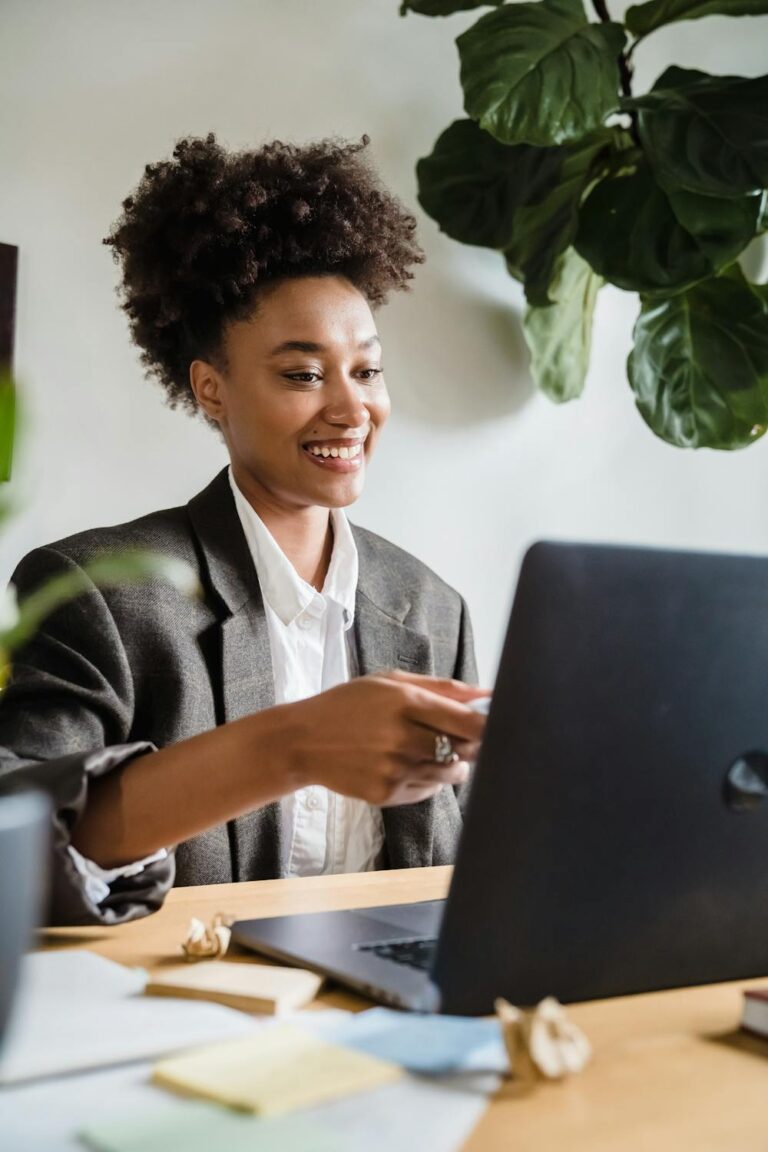 ​"A smiling professional woman working on a laptop in a bright office, representing Nasra using AI productivity tools in 2026."